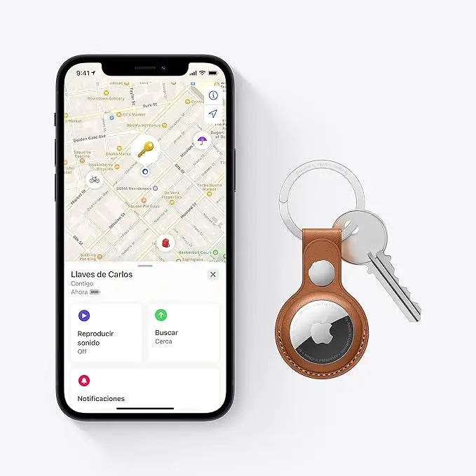 iPhone mostrando la app Find My con un AirTag de Apple en un llavero de cuero, destacando cómo funciona el rastreo de objetos en tiempo real.